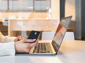 a person holding a credit card and using a laptop
