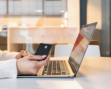a person holding a credit card and using a laptop