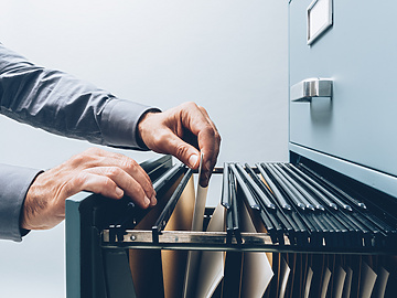 person's hands retrieving paper work from filing cabinet