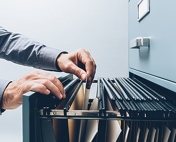 person's hands retrieving paper work from filing cabinet