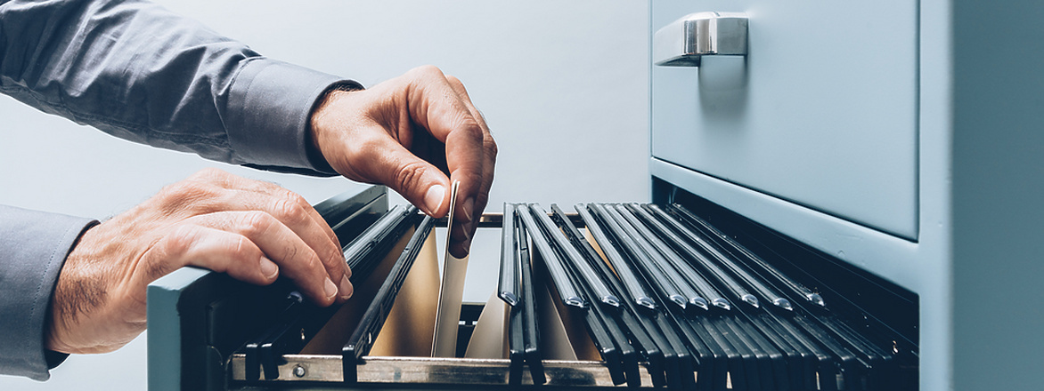 person's hands retrieving paper work from filing cabinet