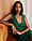 A woman with straight shoulder-length black hair sits on a mustard-yellow couch, leaning against a wooden wall.