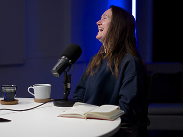 a person sitting at a table with a microphone and a book