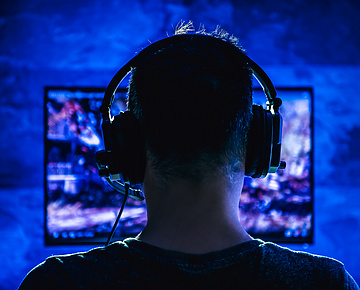 Male with headphones playing online video game on computer