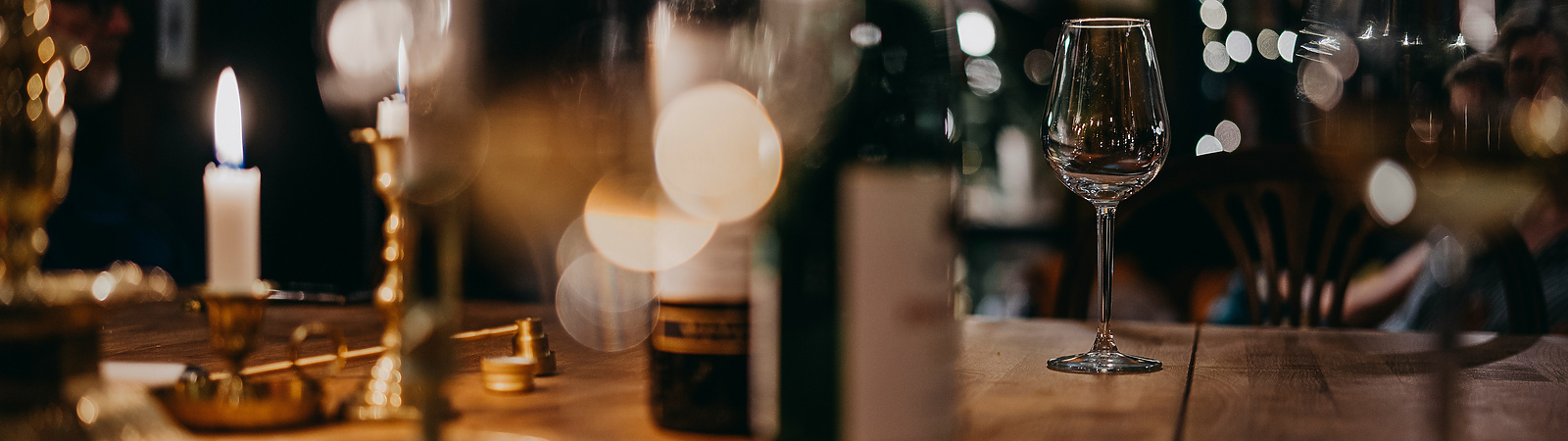 a wine glass and bottles on a table