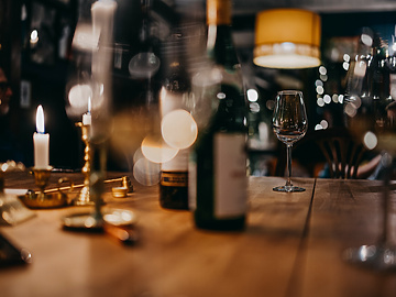 a wine glass and bottles on a table