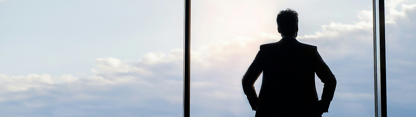 A man looking out of a glass building over a city