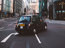 Black cab turning right with St Mary Axe in the background