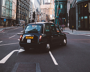 Black cab turning right with St Mary Axe in the background