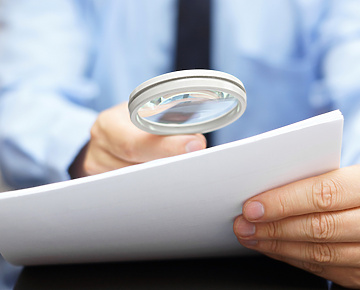 Person using magnifying glass to look at document