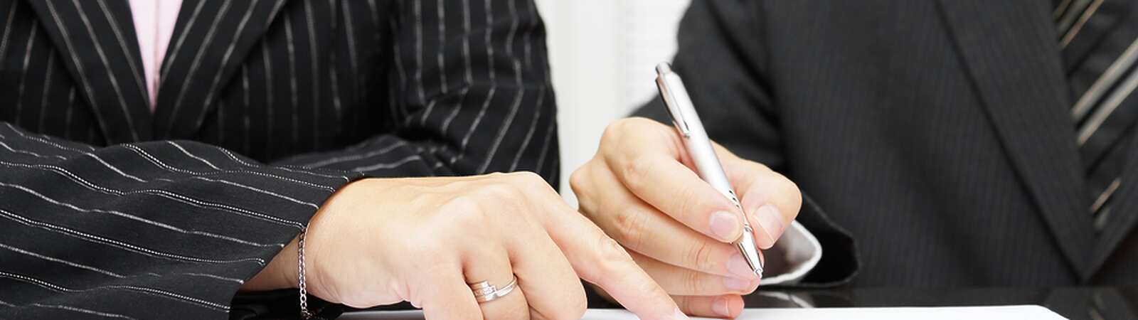 a close-up of a person and a person signing papers