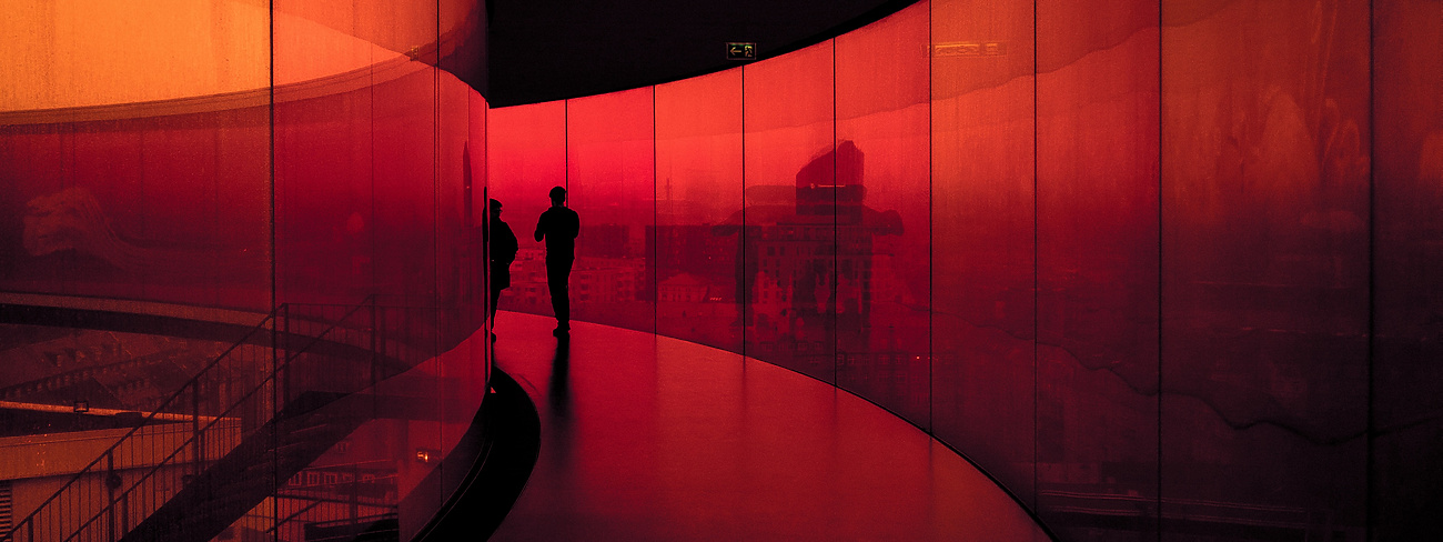 Two people walking along corridor in curved building