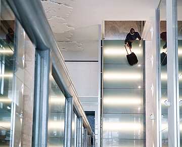 man walking in lobby with suitcase