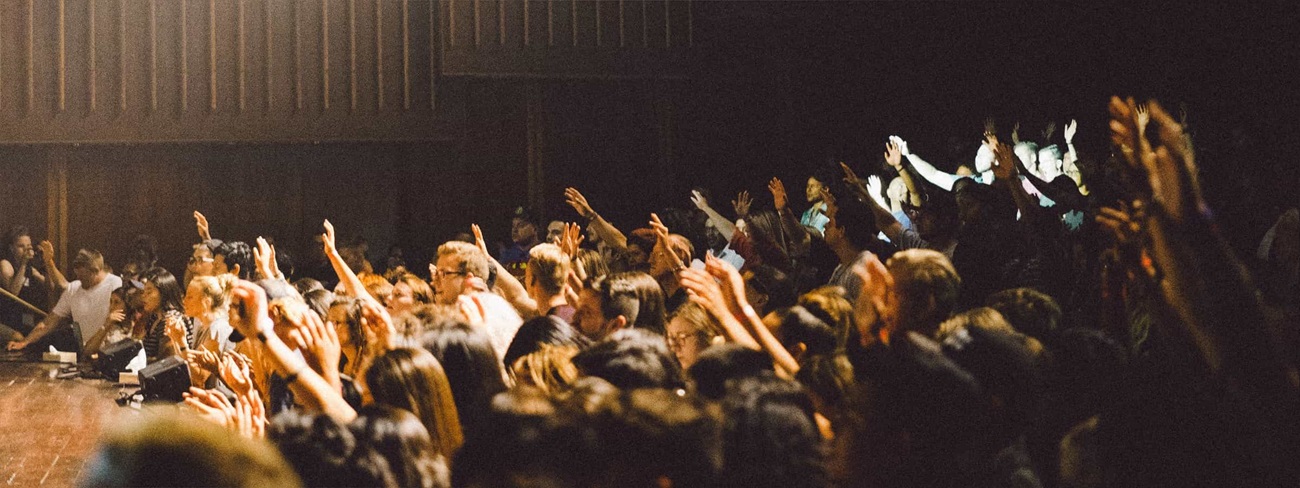 group of students in a hall with hands up