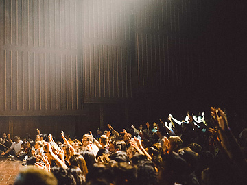 group of students in a hall with hands up
