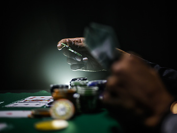 a person holding playing cards at a gambling table