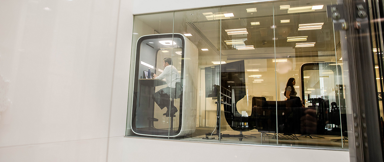 a person sitting at a desk in a glass room