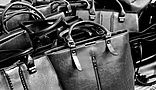 a group of black leather handbags