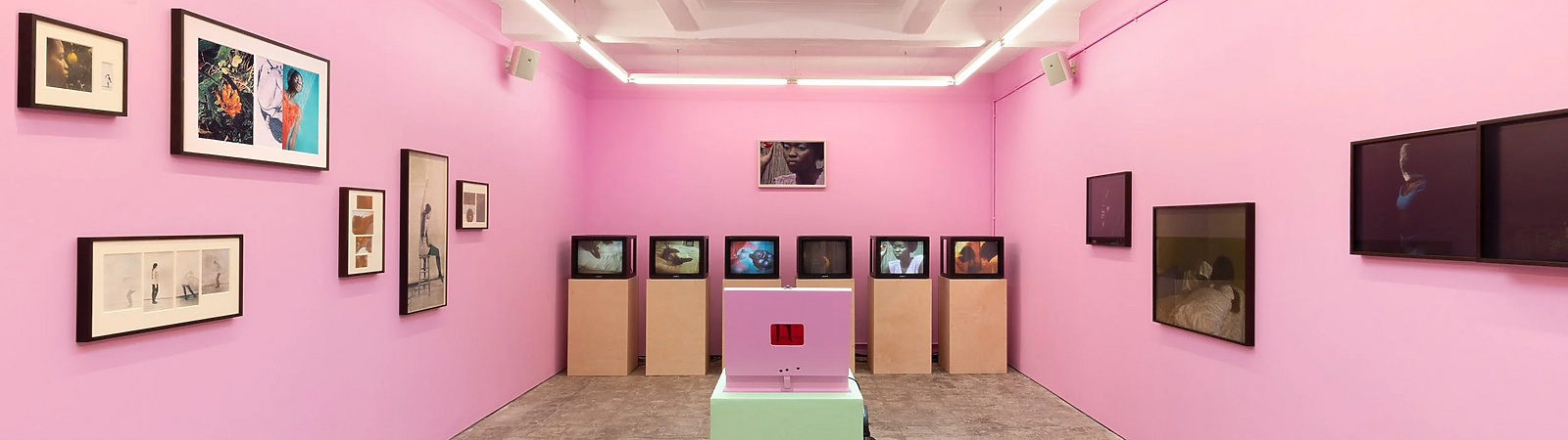 a room with pink walls and a pink table with pictures on the wall
