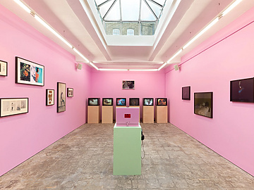 a room with pink walls and a pink table with pictures on the wall