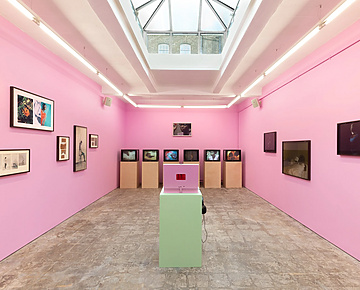 a room with pink walls and a pink table with pictures on the wall