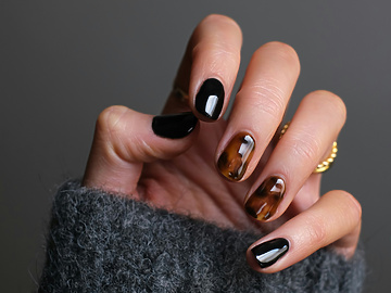 a hand with black and brown painted nails