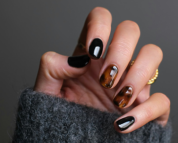 a hand with black and brown painted nails