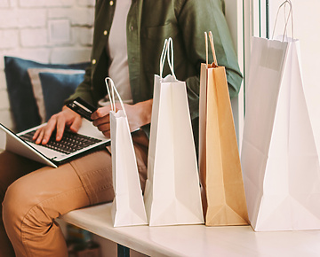 Man working on laptop with four retails bags next to him