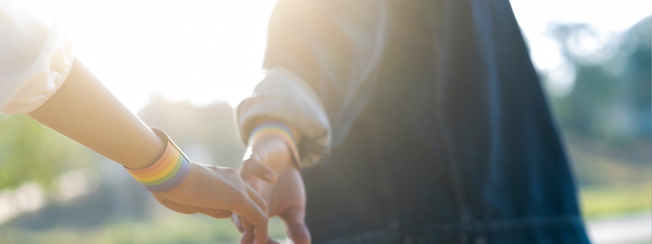 Couple holding hands wearing lgbt bracelets