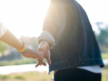 Couple holding hands wearing lgbt bracelets