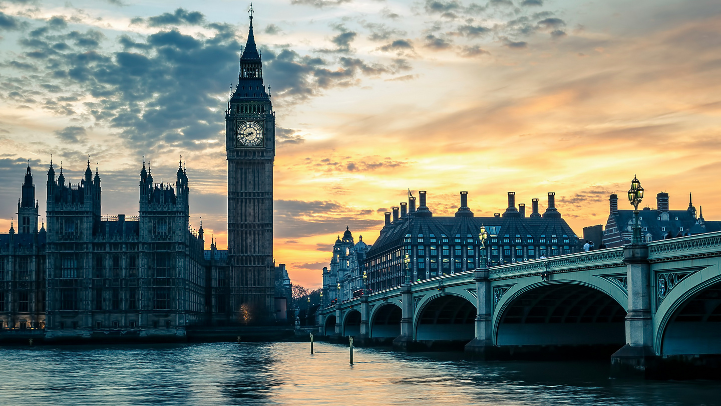 a bridge over water with a clock tower in the background