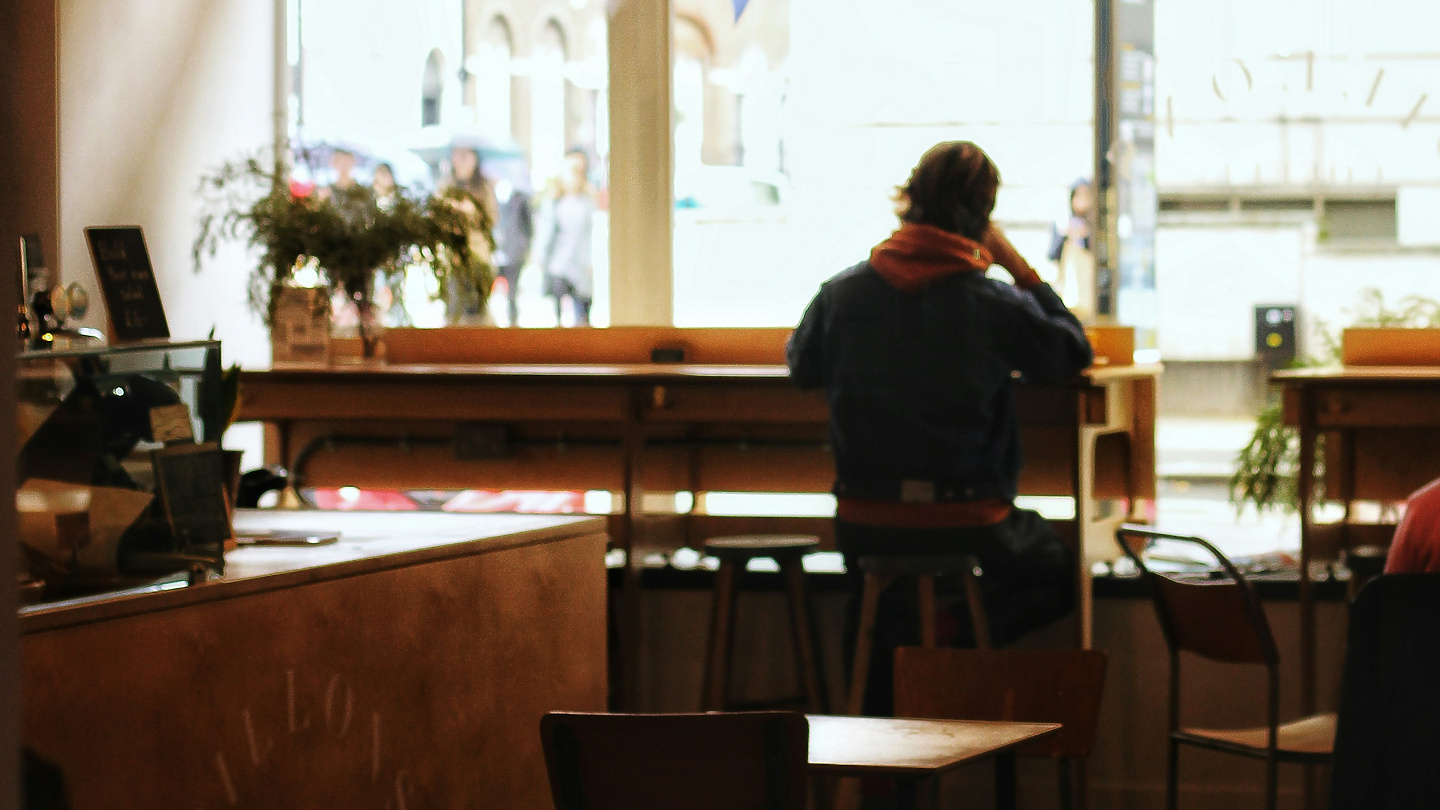 a person sitting at a table in a room with a window